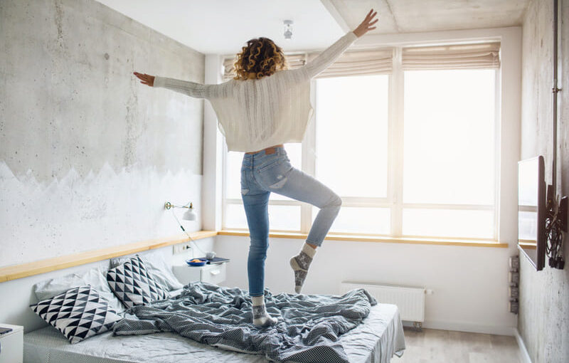 Mujer saltando en una habitación con luz natural