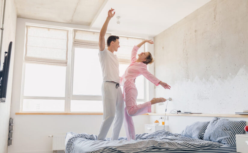 pareja dando saltos en la cama de matrimonio